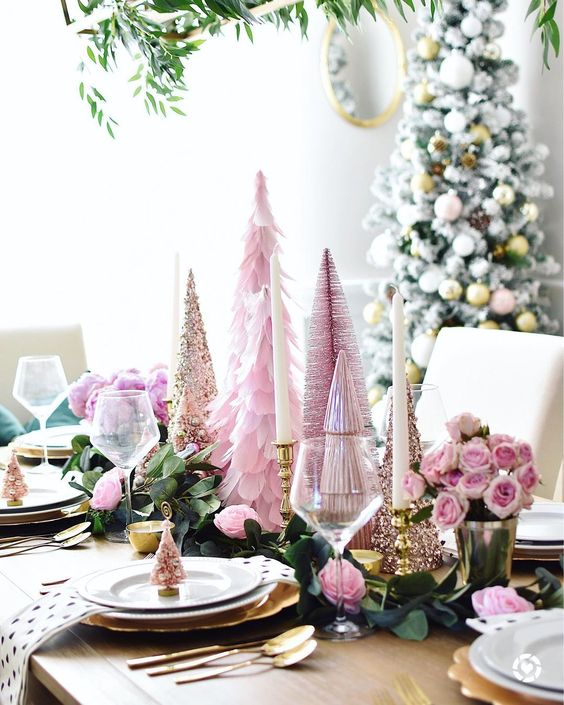 a glam pink Christmas tablescape with faux cone trees, candles, gold chargers, printed napkins and greenery and pink roses