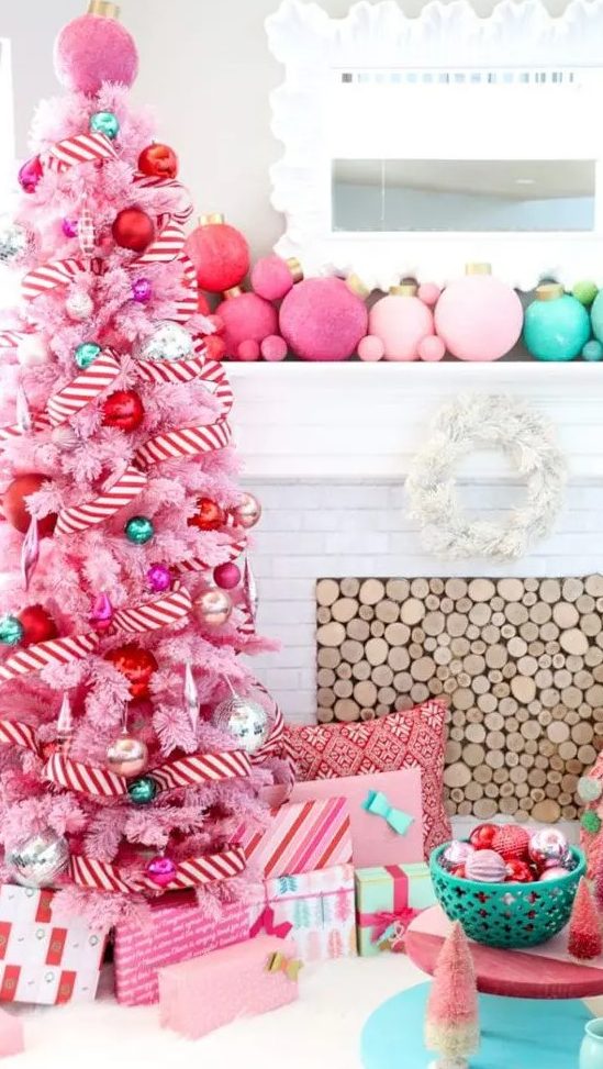a pastel pink Christmas tree decorated with pink, red, green and silver ornaments and with a striped garland is pure fun and glam