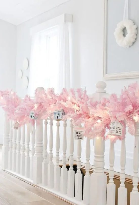a pastel pink evergreen garland on the railing, mini houses and lights is gorgeous Christmas decor you can easily make