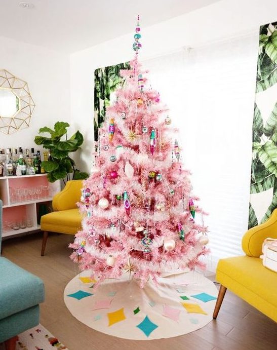 a pink Christmas tree with colorful ornaments and lights, with gold touches looks pretty and very chic
