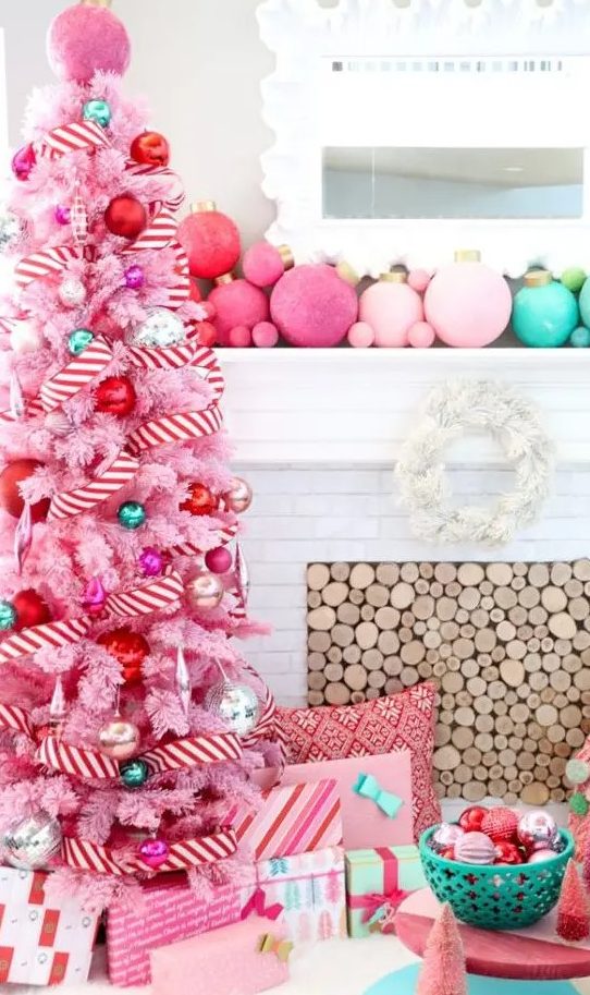 a pink Christmas tree with pink, red, green and silver ornaments and a striped red and white ribbon plus an orange topper is amazing