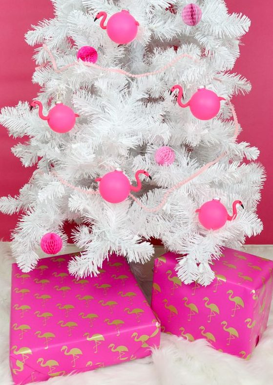 a white Christmas tree decorated with hot pink paper pompoms and flamingo-shaped ornaments is a fun idea for a tropical holiday space