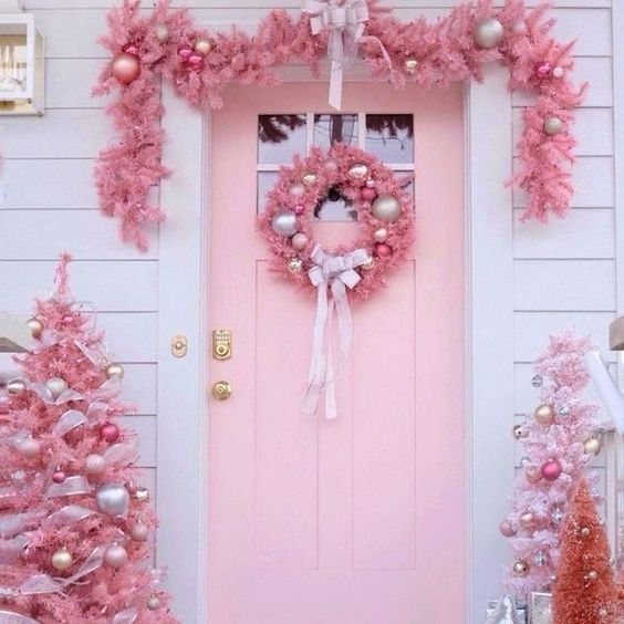 pink Christmas outdoor decor with trees and silver and pink ornaments, a pink wreath and a garland and some ornaments