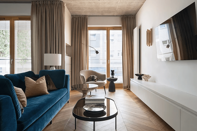 03 The living room features a white sleek TV unit, a navy velvet sofa, a built-in storage unit and a cozy chair by the window
