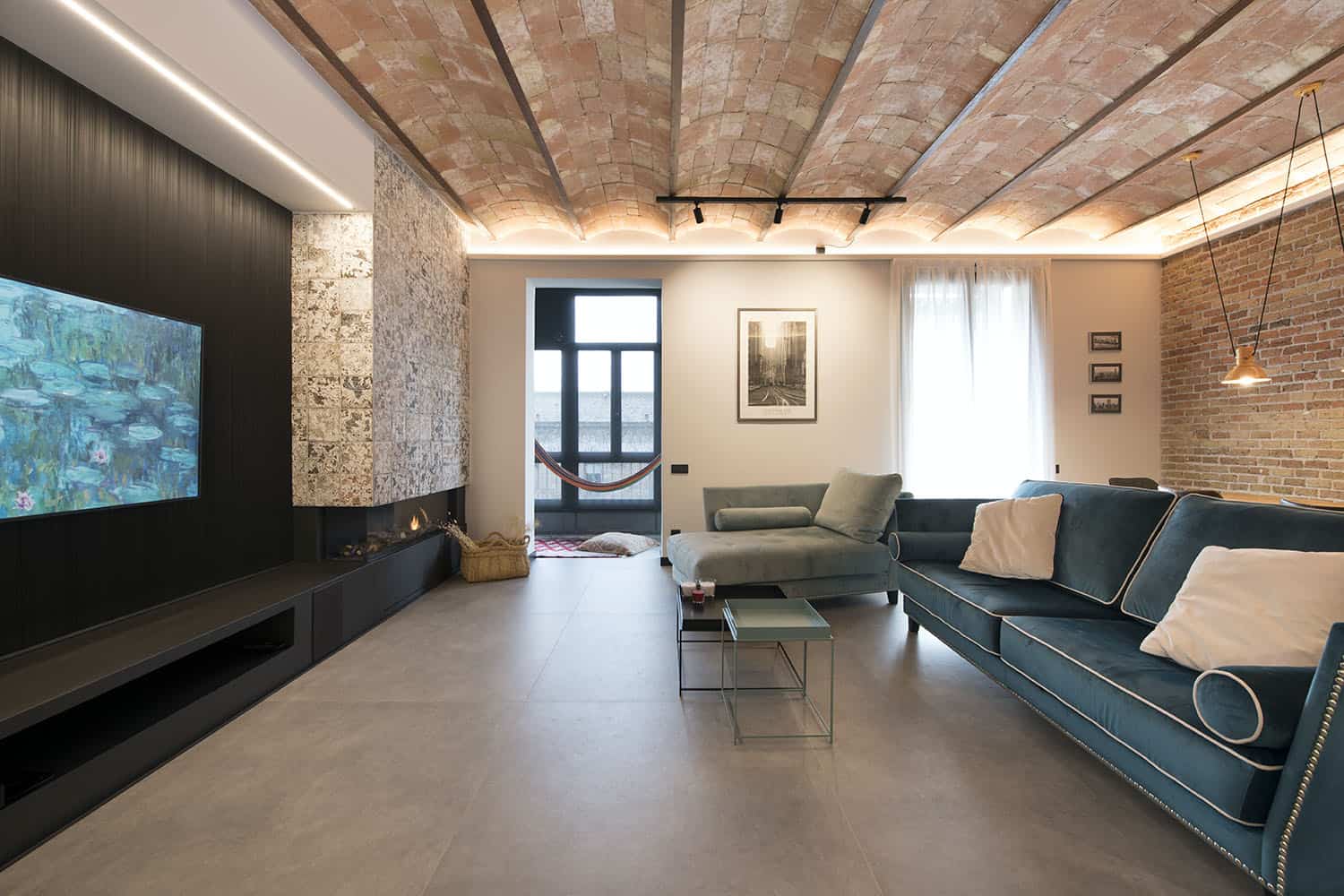 The living room was done with brick walls and a ceiling, a black accent wall, a built-in fireplace and a balcony