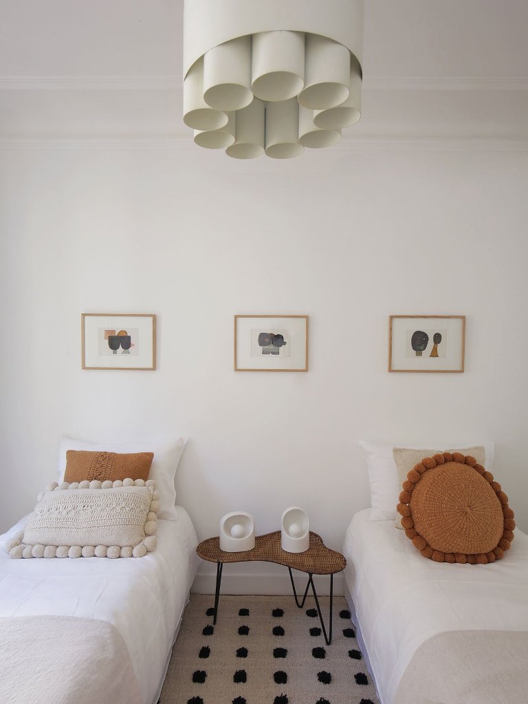 The guest bedroom shows off a woven table, a cool tube chandelier and some bright touches