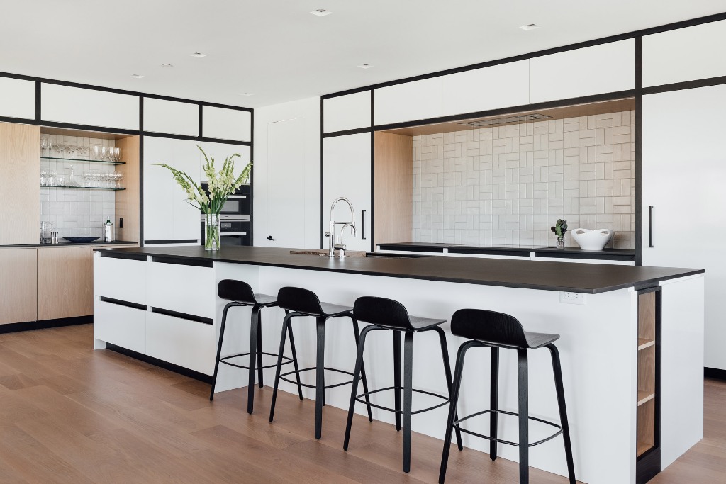 The kitchen is done in warm neutrals and white, with black edges, black countertops and stools