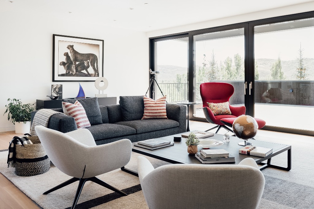 The living room is done with grey furniture, a bold red chair, potted plants and is opened to the terrace The living room is done with grey furniture, a bold red chair, potted plants and is opened to the terrace