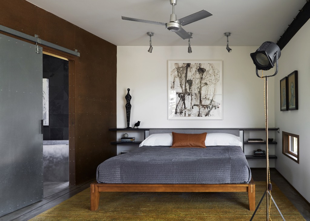The bedroom is very laconic, with a bed, some open shelves, an artwork and lamps