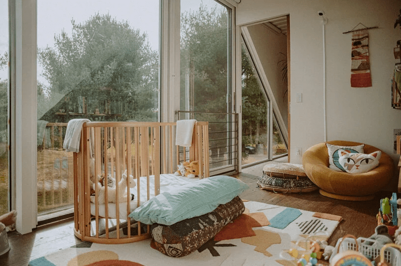 The nursery is done with a glazed wall, some pretty boho furniture and poufs, a crib and colorful toys and rugs