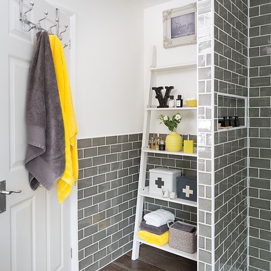 a bathroom clad with grey tiles, with white furniture and grey and yellow accessories and accents looks very bold