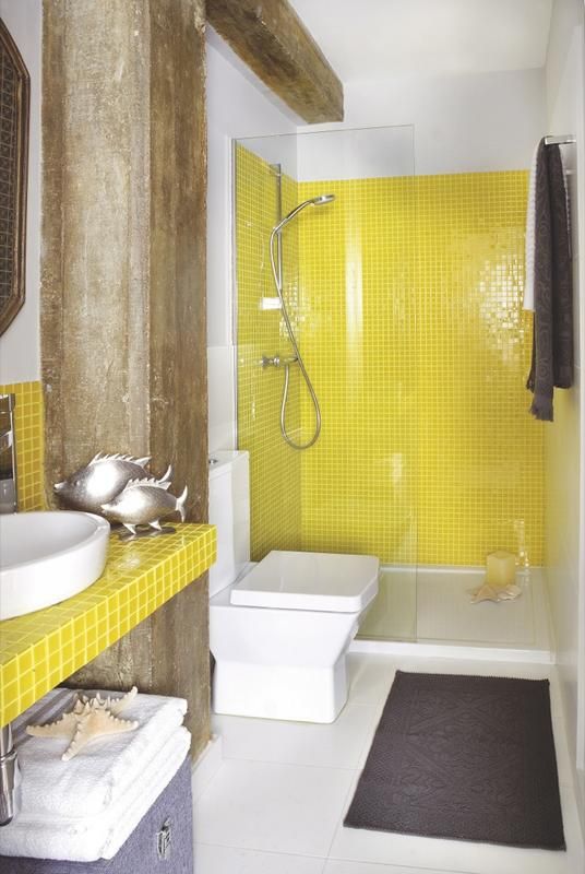 a bold bathroom with white walls, lemon yellow tiles, rough wooden beams, grey upholstery and textiles