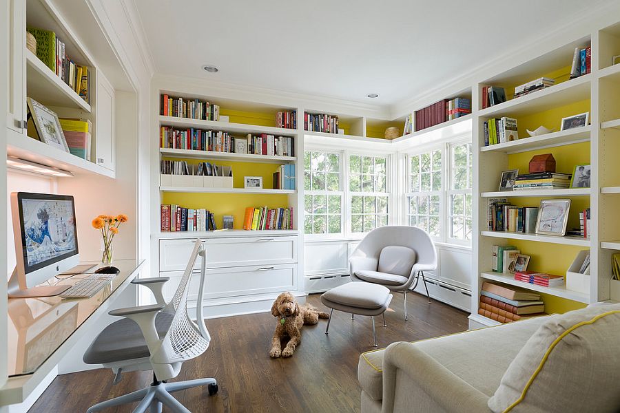 a bright home office with mustard walls and built in shelves, a built in desk, a grey chair, a lovely creamy one and a grey and yellow sofa