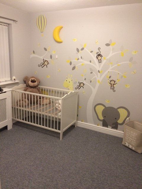 a dove grey nursery with a tree with yellow and grey decals, neutral furniture, bright yellow touches is very relaxing