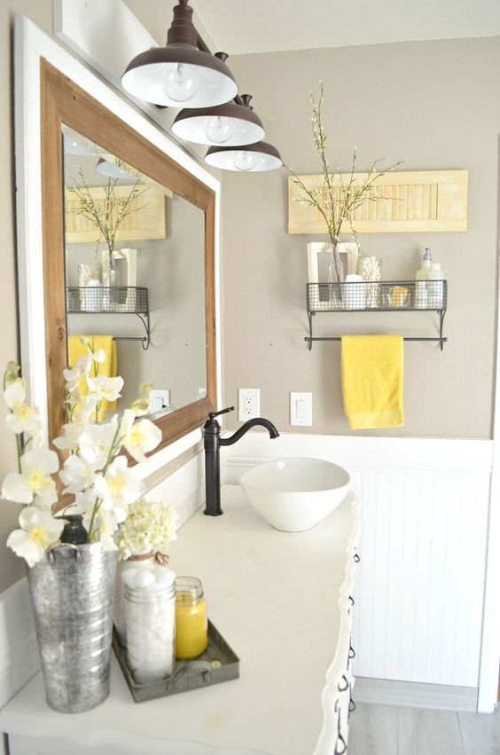 a farmhouse bathroom with grey walls, white furniture and appliances, a mirror, retro lamps and retro shelves