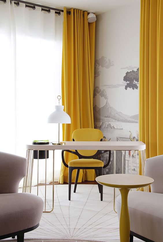 a jaw dropping refined home office with a whimsy desk, a couple of blush chairs, a lemon yellow chair and curtains plus a grey and white artwork on the wall