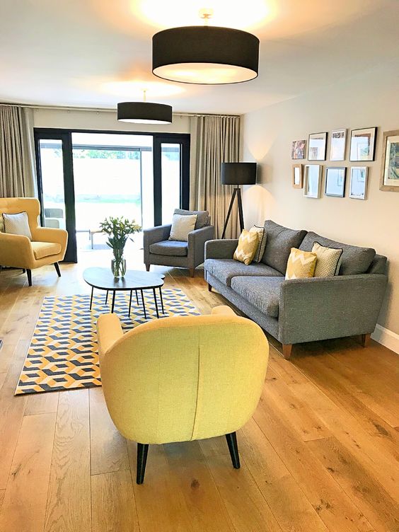 a modern living room with buttermilk walls, a grey sofa and a chair, bold yellow chairs and black and yellow accessories