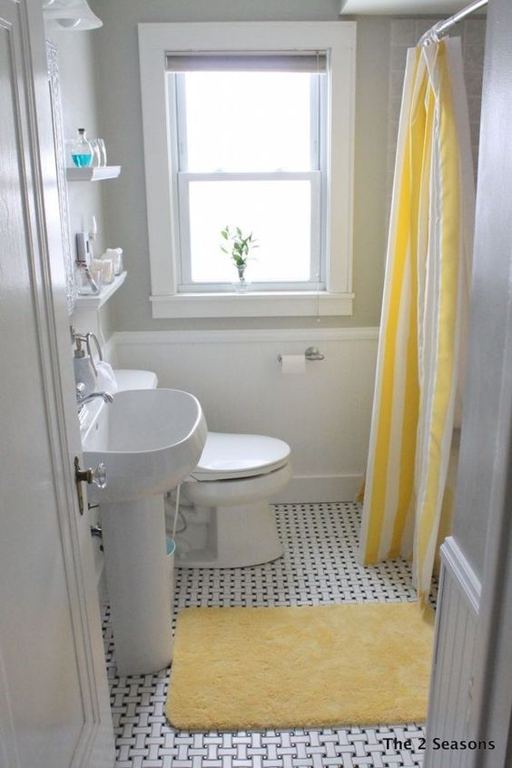 a small bright bathroom with grey walls and white paneling, wihte appliances, bright yellow textiles is super cool