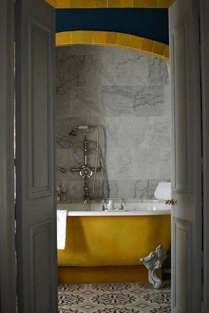 a vintage bathroom clad with grye marble tiles and patterned ones, a yellow clawfoot tub, elegant fixtures is very chic