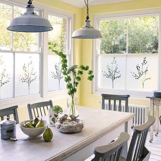 a vintage dining space with yellow walls, a white table, some grey chairs and pendant lamps, a wooden console table