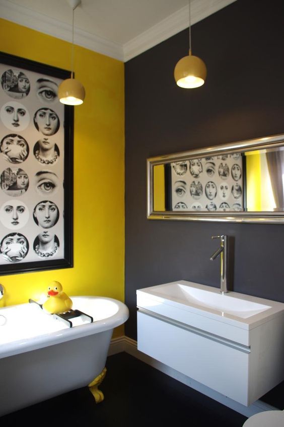 a whimsical bathroom with grey and yellow walls, white appliances, yellow pendant lamps and a bold and quirky artwork