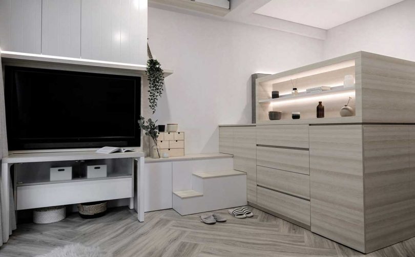 There's an elevated bed with plenty of open and closed storage units, built-in lights and a TV next to it