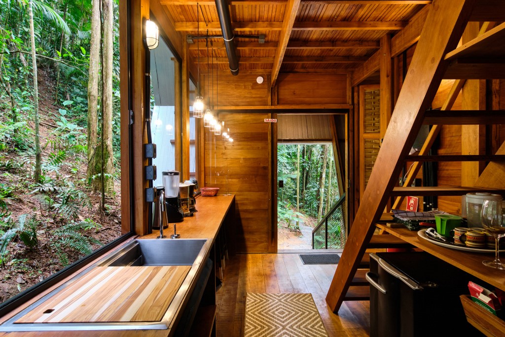 03 Inside everything is clad with rich-stained wood, there’s a galley kitchen with lights and a glass wall