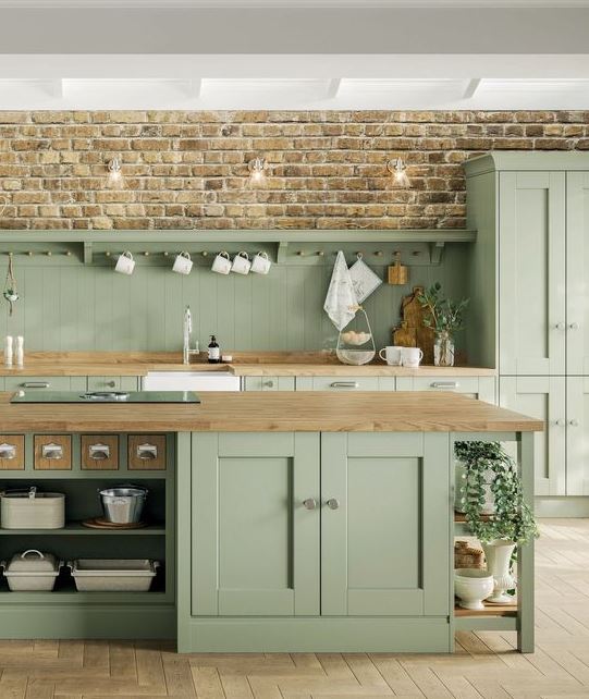 a rustic sage green kitchen with elegant vintage cabinetry, wooden countertops and neutral fixtures and handles