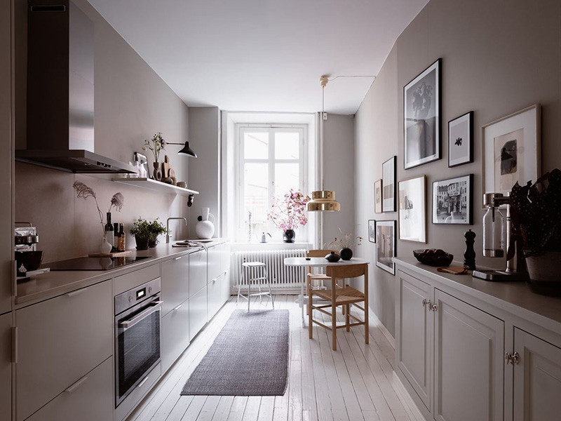 04 The kitchen is done with modern and vintage grey cabinetry, with a mauve backsplash and a large gallery wall