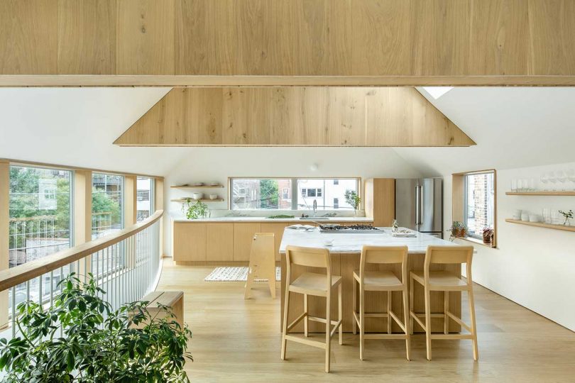 The kitchen is minimal, with light-stained cabinets with white stone countertops and a kitchen island with a breakfast zone