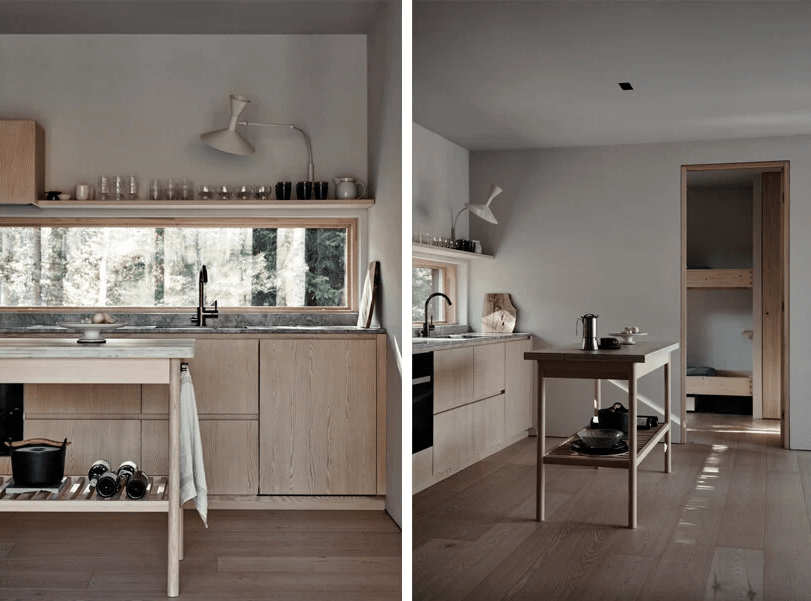 The kitchen is sleek and contemporary, with light-stained wooden cabinets and a window as a backsplash