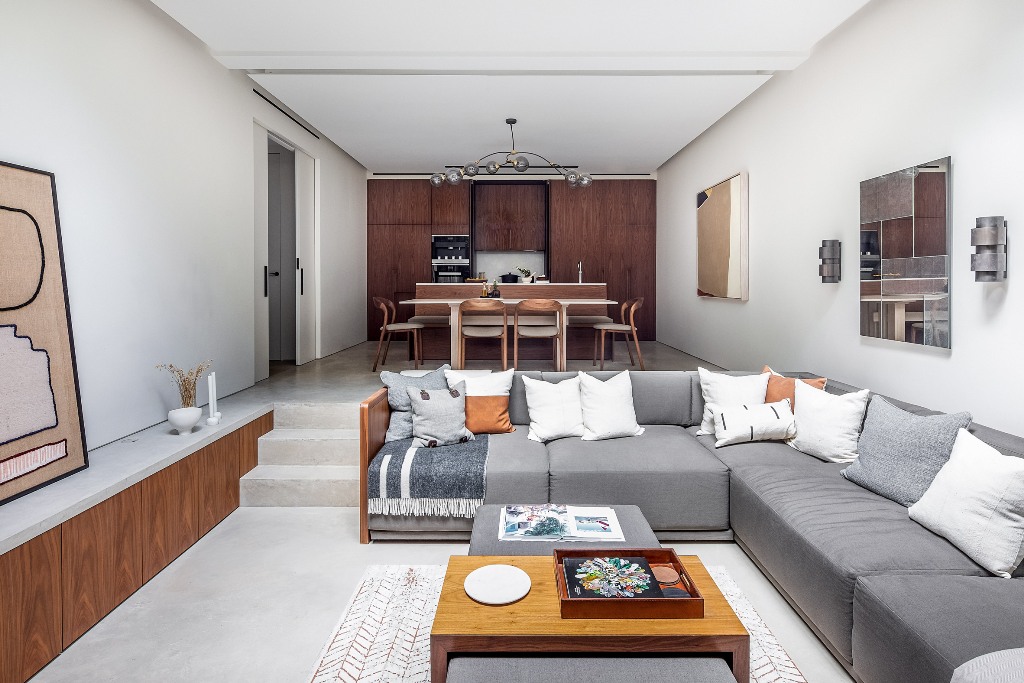 There's a kitchen and sunken seating area in the basement, it features chic furniture, stained wooden cabinets and catchy textiles