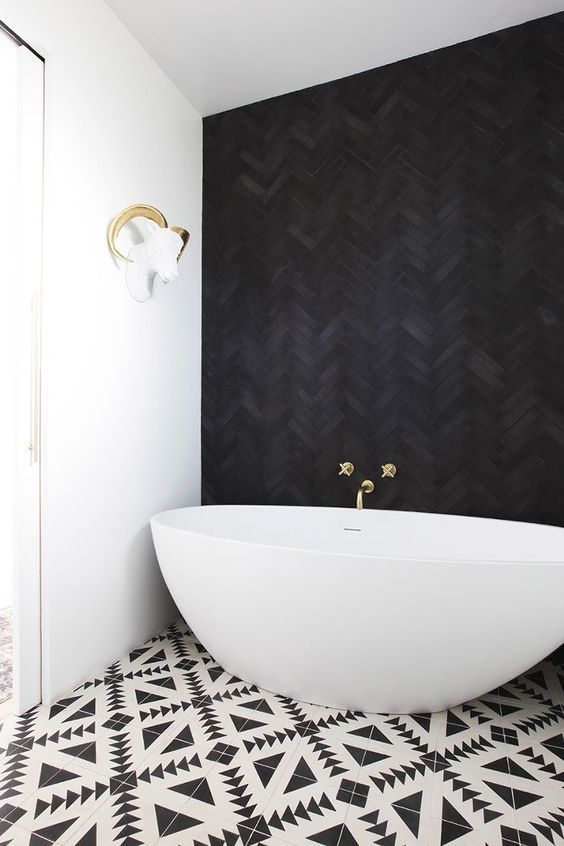 04 a jaw-dropping bathroom with a black herringbone tile wall, geometric printed tiles and a cool oval bathtub