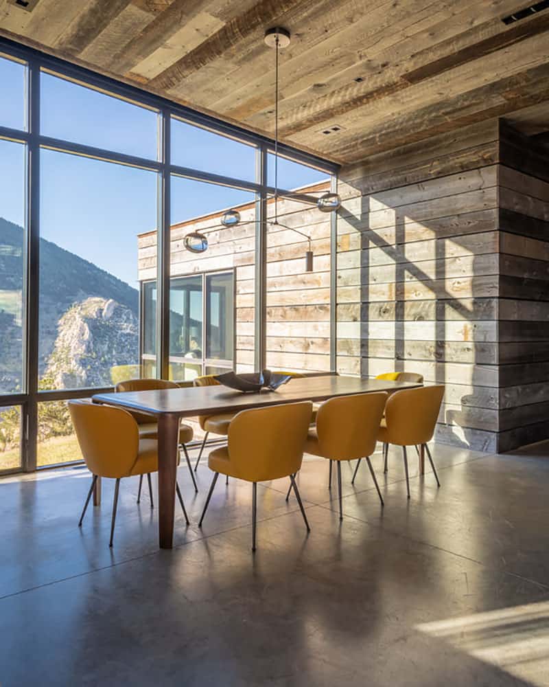 05 The dining space is located next to a glazed wall, a wooden table and yellow chair plus a cool chandelier