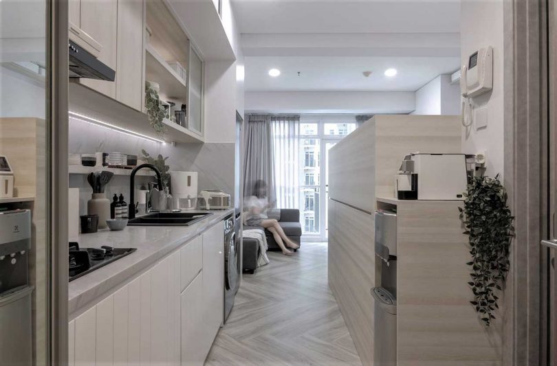 The kitchen is done with white cabinets, white stone countertops and lights plus black fixtures