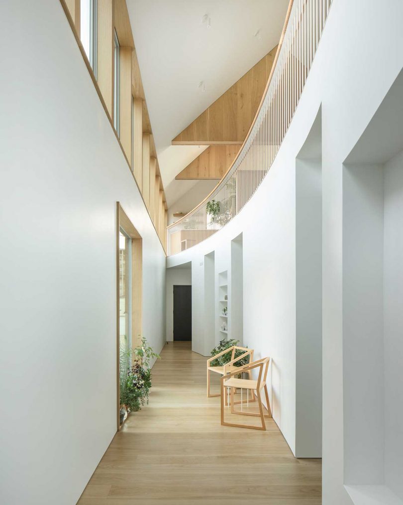 There's a curved balustrade and a small corridor with storage spaces, chairs and potted plants