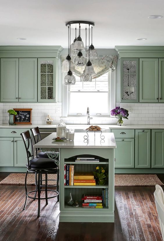 10 a chic vintage sage green kitchen with elegant cabinetry, a white tile backsplash and countertops, a small kitchen island with storage