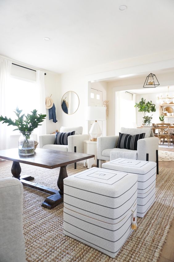 a neutral global style living room with pretty Moroccan-inspired ottomans, a wooden table and pretty pillows