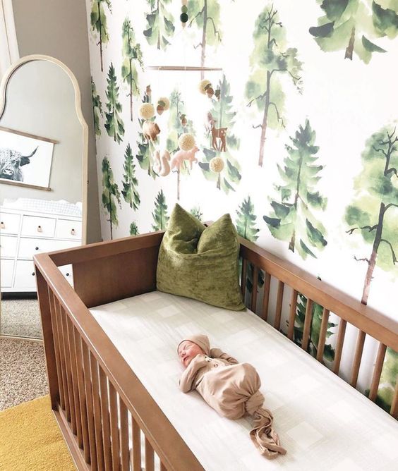 a cool woodland nursery with lovely forest wallpaper, wooden furniture and earthy textiles