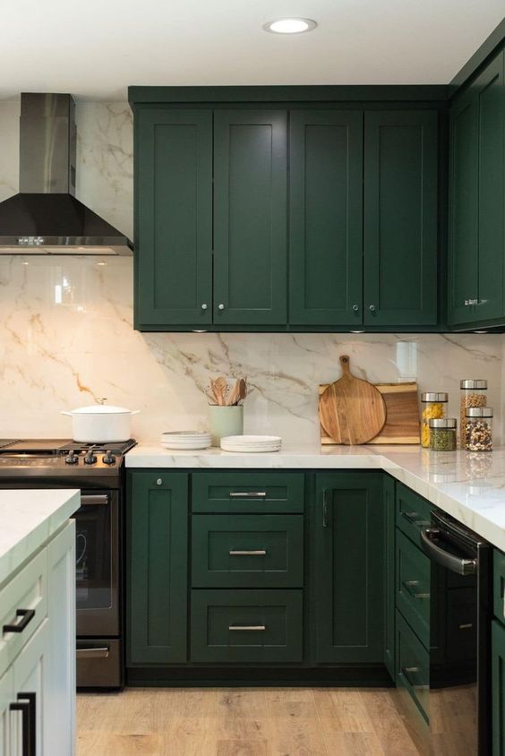 an elegant hunter green kitchen with a white marble backsplash and countertops and a white kitchen island for a contrast