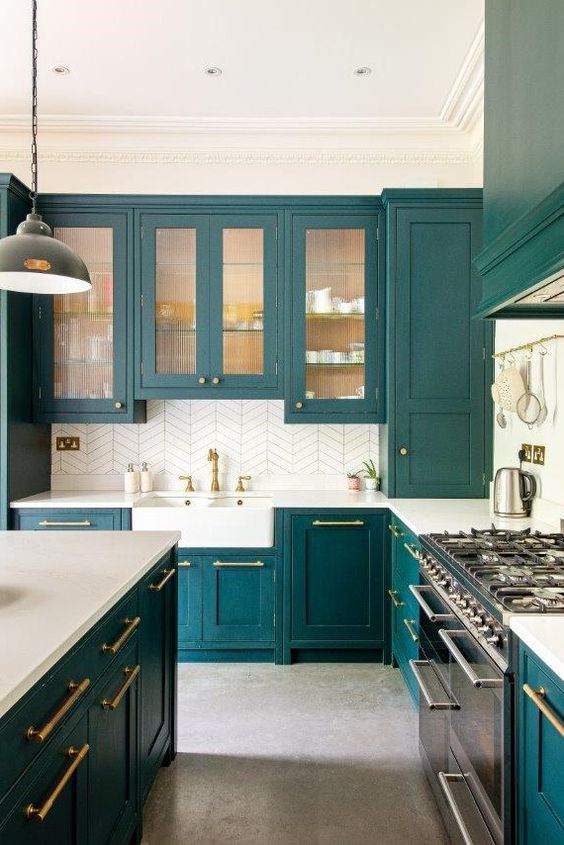 23 a teal kitchen with glass and usual cabinets, white countertops and a white tile backsplash, gold fixtures and handles