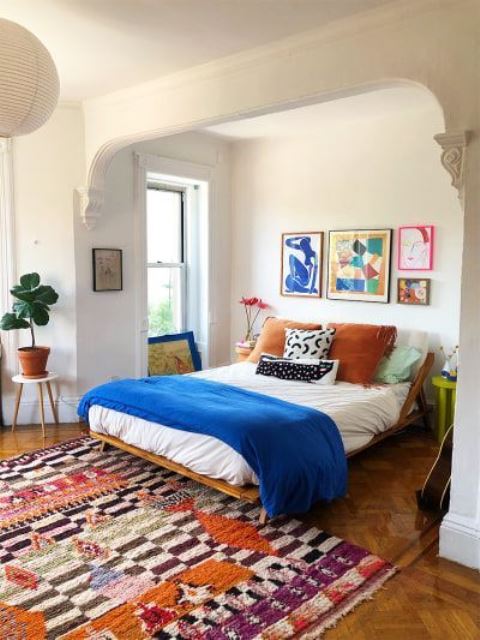 a colorful modern bedroom with a bright gallery wall, bold bedding and textiles and potted plants