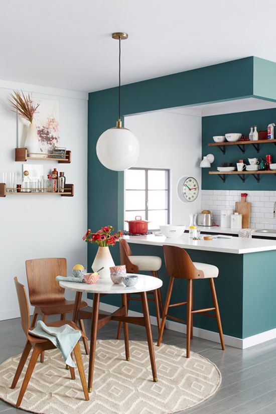 a modern teal kitchen separated from the rest of the space with a kitchen island, with a white tile backsplash and countertops