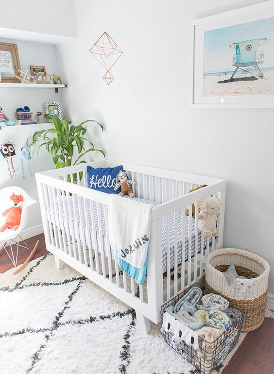 33 a pretty modern beach nursery with a lovely artwork and fun printed bedding, a potted plant and baskets