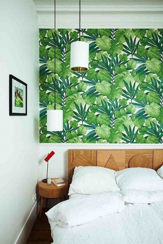 a bold modern bedroom with tropical leaf wallpaper, a catchy wooden bed and round nightstands plus pendant lamps