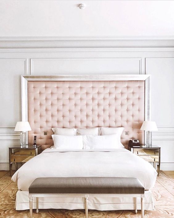a glam bed with an oversized pink tufted headboard with a silver frame sets the tone in this space
