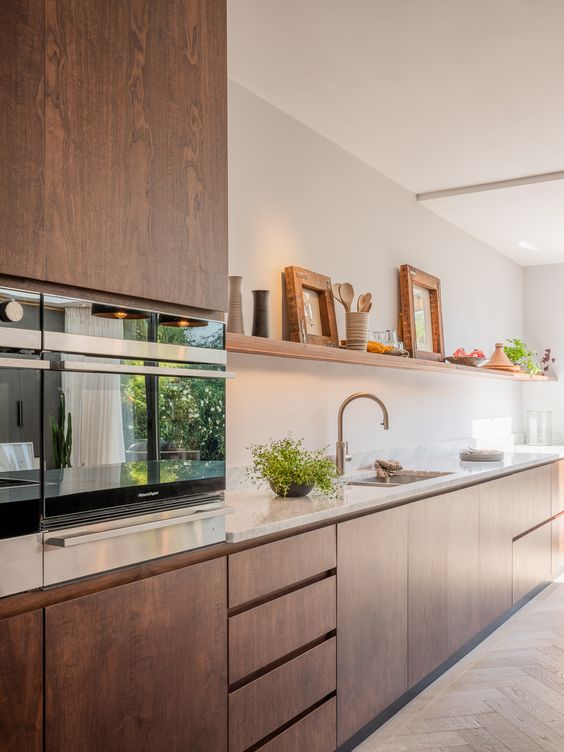 a sleek walnut kitchen with a Scandinavian design, a white tile backsplash and countertops plus touches of gold