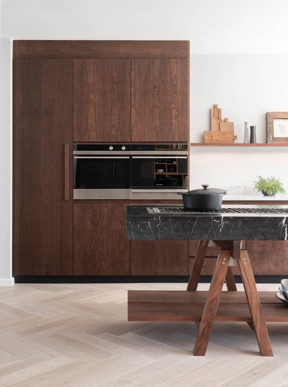 a stunning walnut kitchen with a unique trestle kitchen island topped with black marble looks just amazing