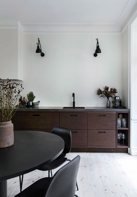 a bold walnut kitchen with dark cabinetry, a grey stone countertop and black fixtures and furniture