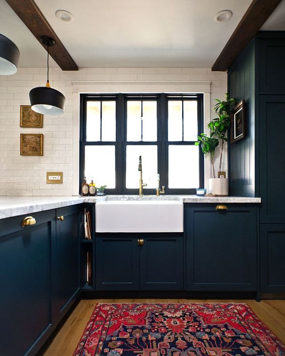 an elegant navy farmhouse kitchen with white stone countertops, a white tile backsplash and dark wooden beams on the ceiling